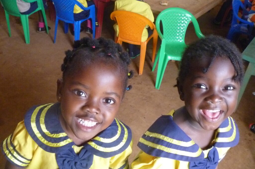 A young African girl in a school uniform holding her school bag, representing a child supported through a child sponsorship programme."